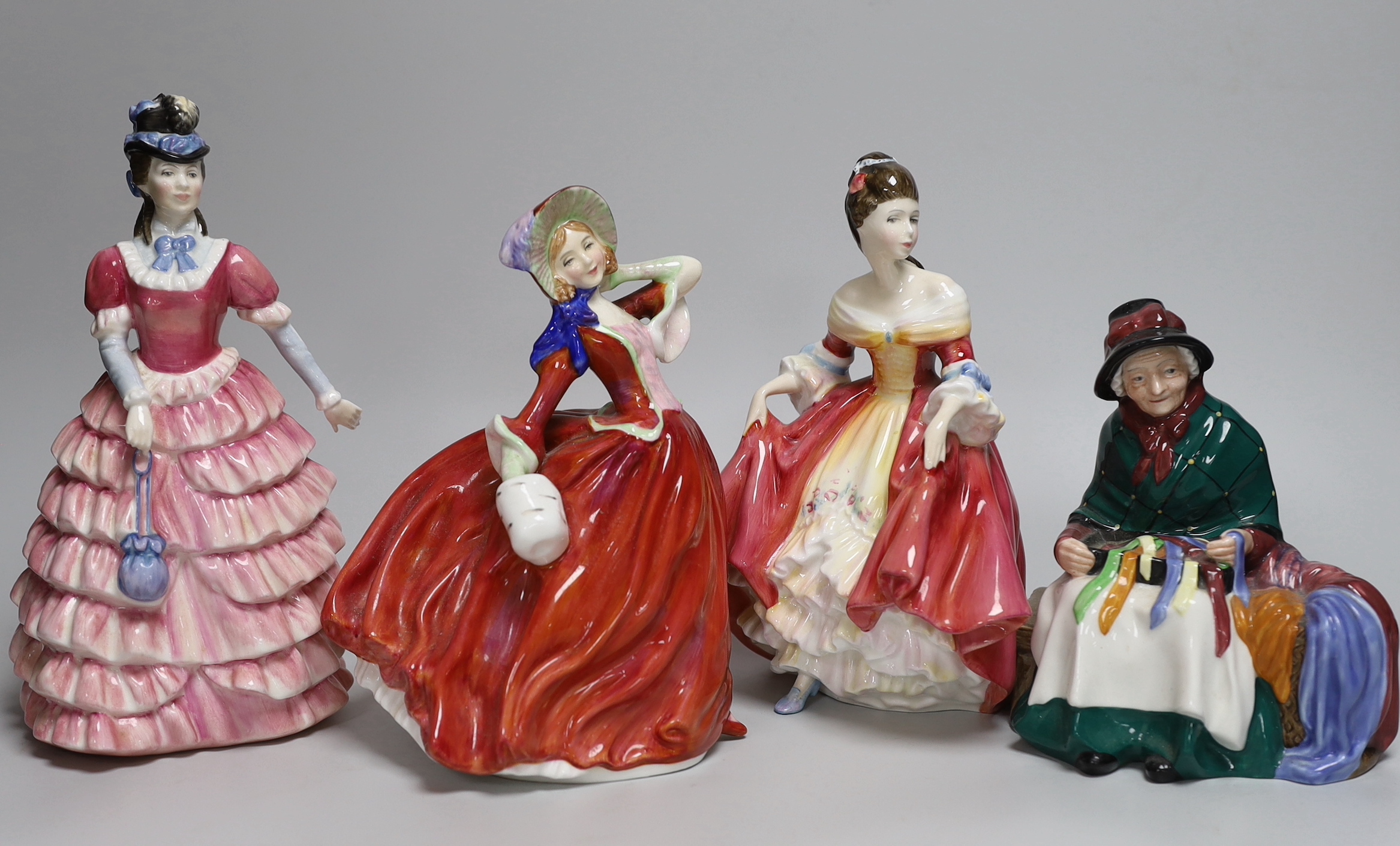 Four Royal Doulton figurines including Autumn Breezes and an oversized Christian Dior advertising scent bottle, Eau Sauvage Extreme, the largest 33cm high